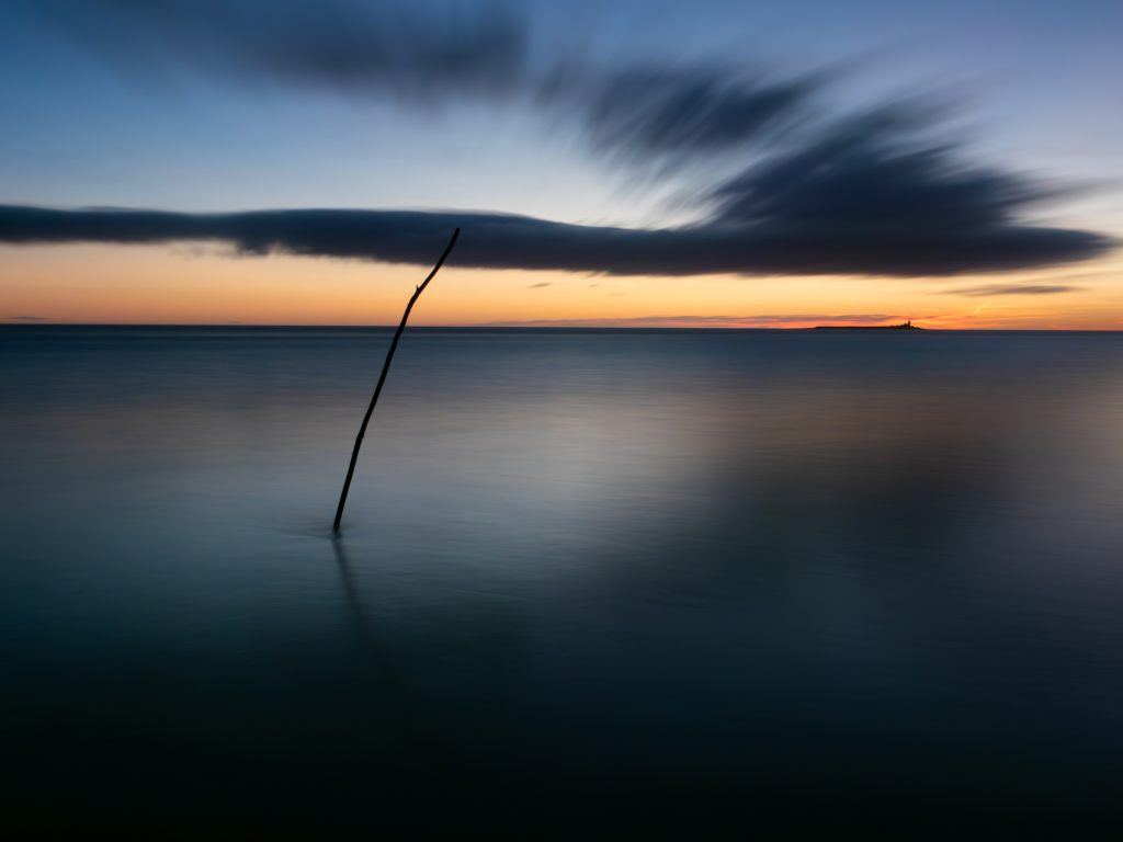 Gift Voucher image. Sunrise over the sea with a pole in the water.