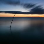 Gift Voucher image. Sunrise over the sea with a pole in the water.