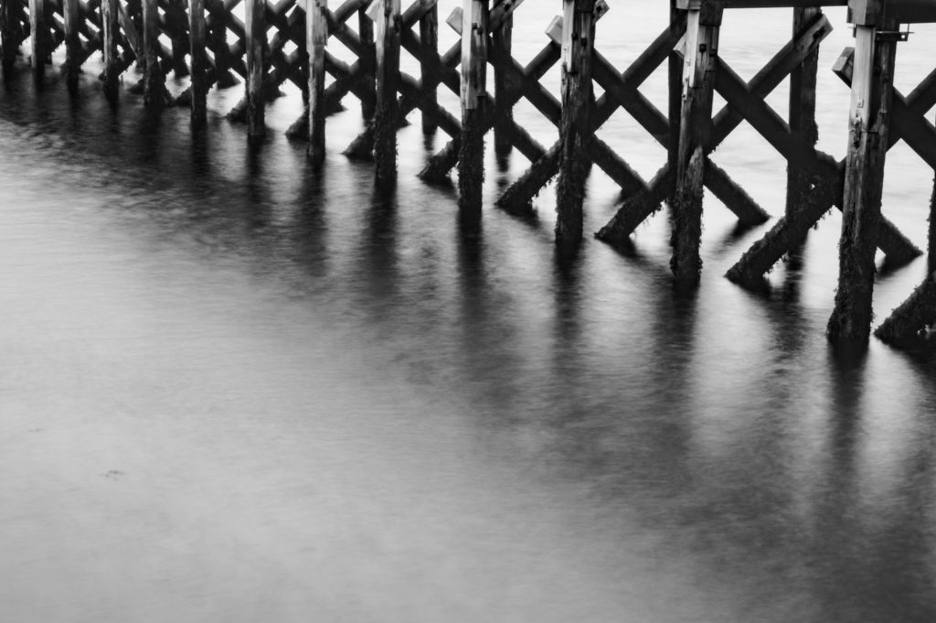 The legs of the pier in monochrome