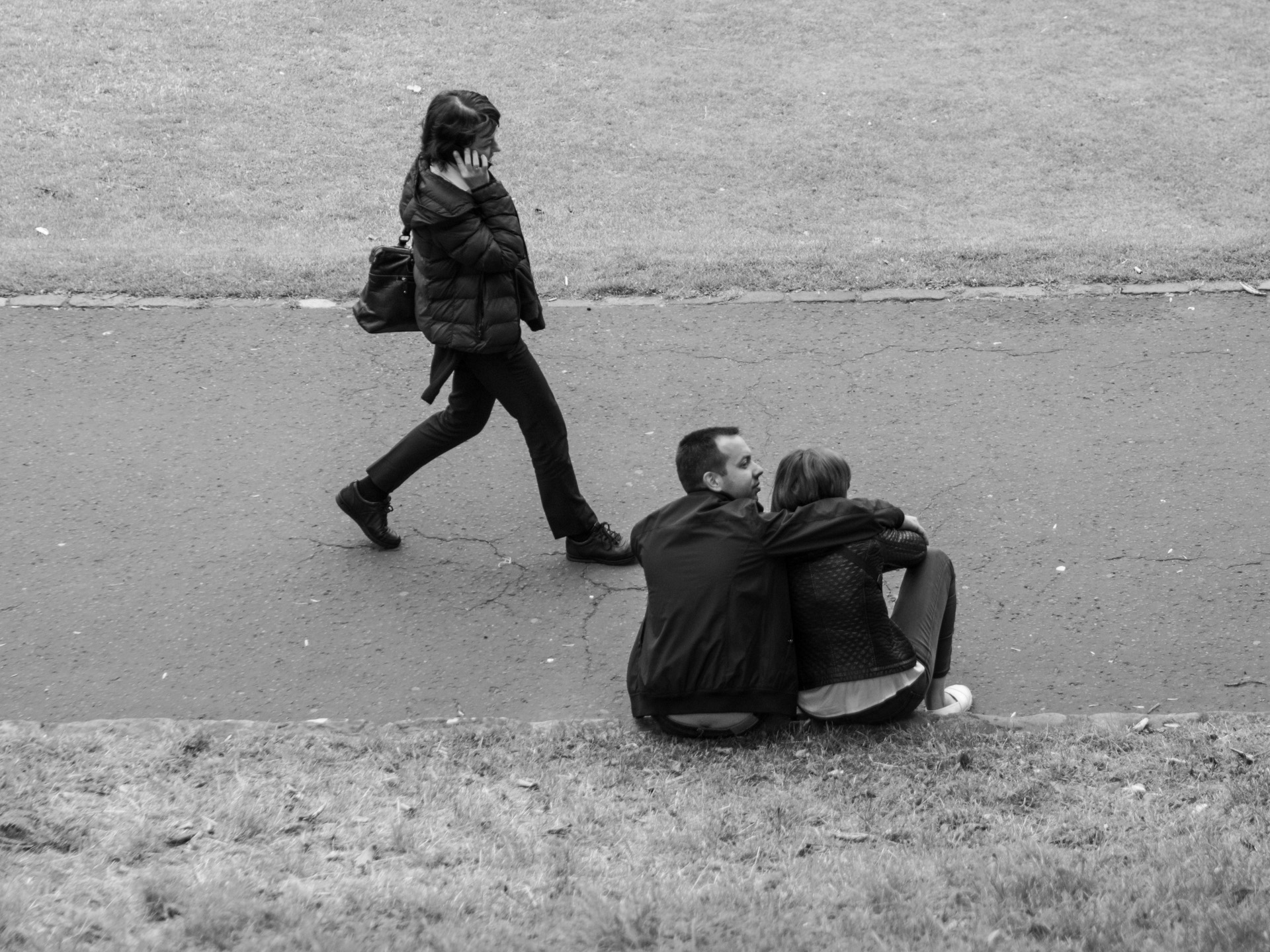 Street photograph in black and white. a couple share a romantic moment while a man walks past. A GCSE photo