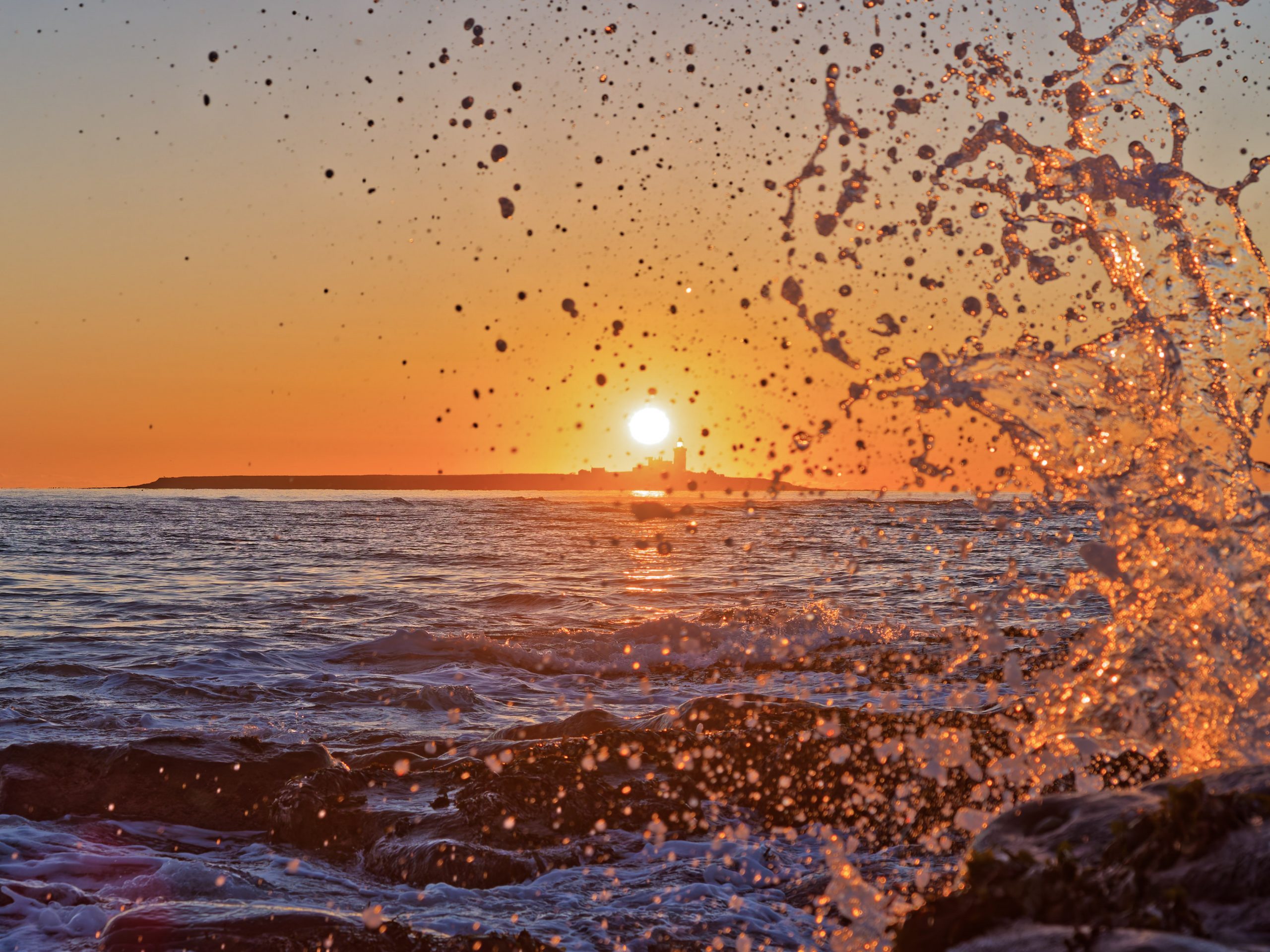 On a Landscape and Panorama workshop, we may take photos of the sun rising behind Coquet Island plus a splashing wave in the foreground. Orange sky.