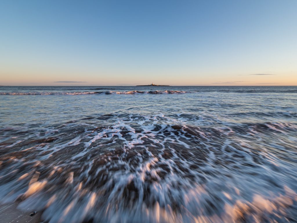 Shot on Northumberland Photography Workshops, images of the coast like this one showing waves moving towards the camera. They are lit by low-angled light.
