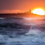 Sunrise telephoto shot taken on a Northumberland Telephoto photography workshop. The sun rises behind Coquet Island while the sea splashes in front.